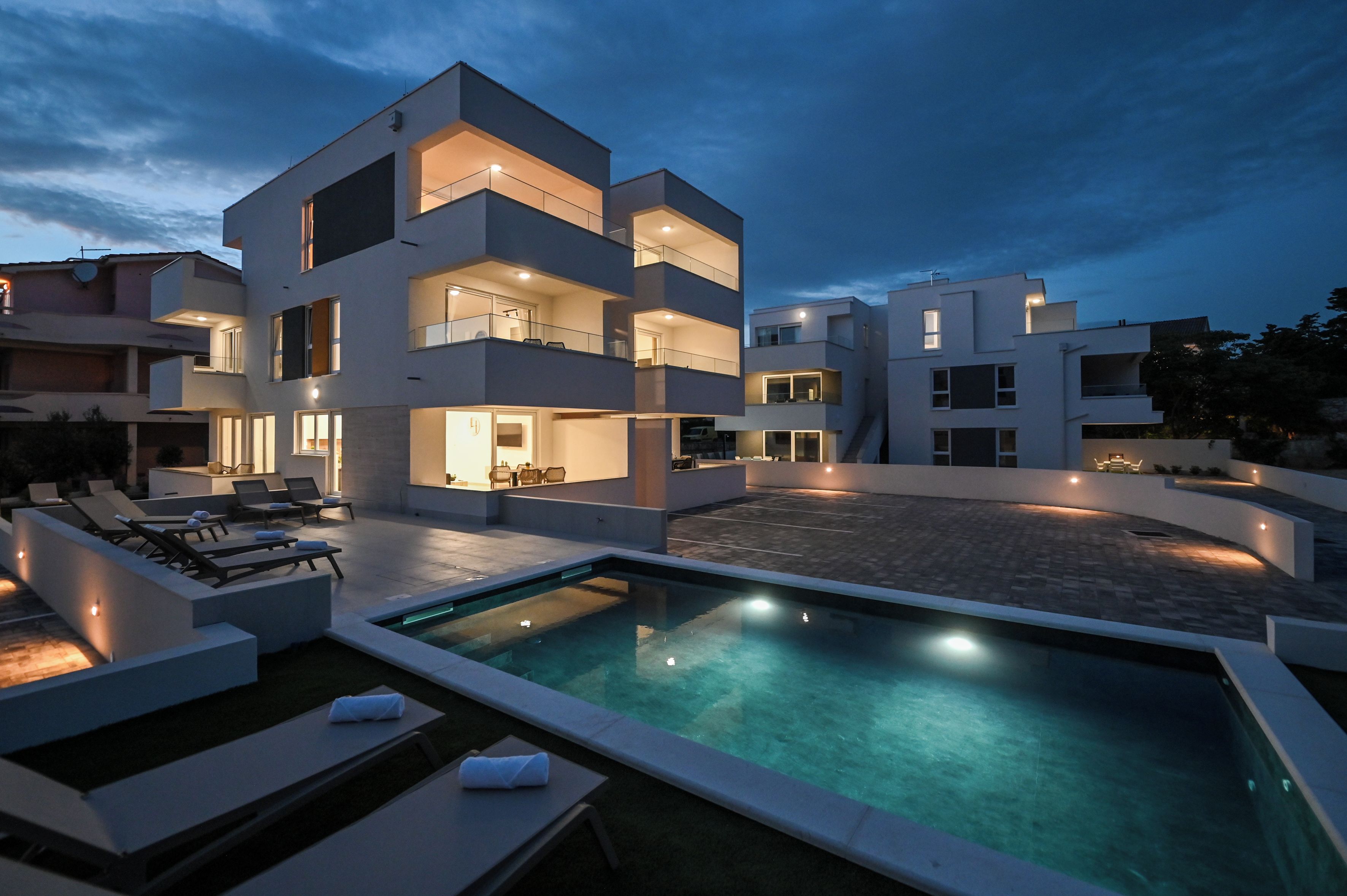 A modern multi-story building with a swimming pool and outdoor seating area.