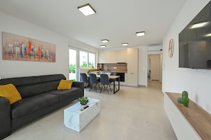 A modern living room with a sofa, coffee table, and a dining area with chairs and a table. - Apartment Break with Private jacuzzi (Novalja)