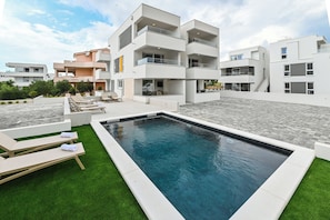 A modern residential building with a swimming pool, outdoor seating, and a well-maintained lawn. - Apartment Break with Private jacuzzi (Novalja)
