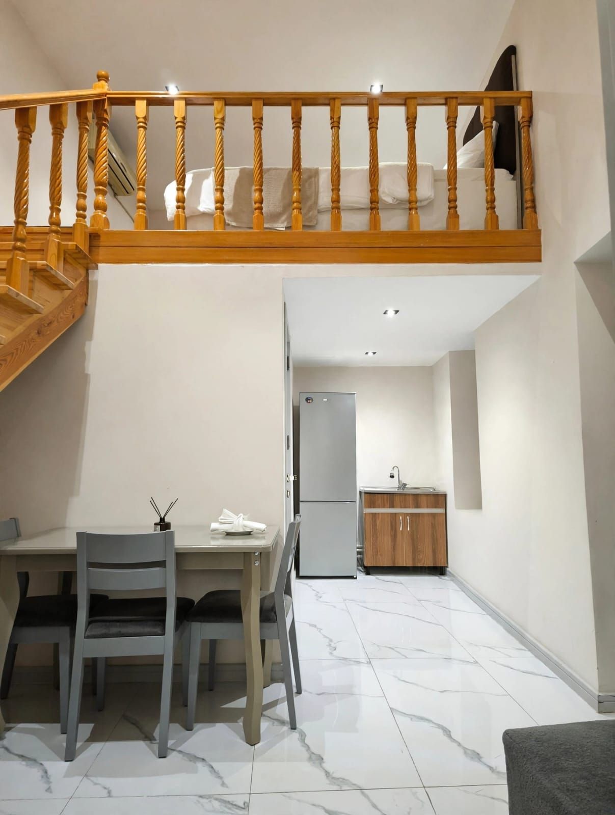 A dining area with a table and chairs, a kitchen with cabinets, and a wooden staircase.