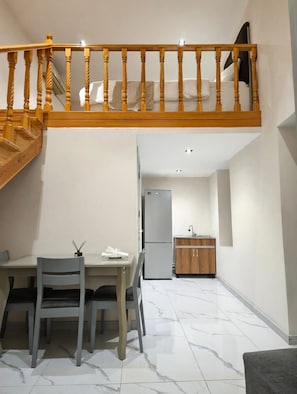 Un comedor con mesa y sillas, una cocina con armarios, y una escalera de madera.