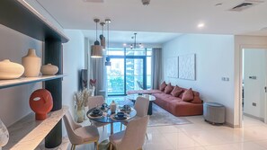 Een moderne woonkamer met een eethoek, een zithoek en een groot raam met uitzicht op de stad.