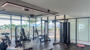 Een moderne sportschool met diverse fitnessapparaten, grote ramen en uitzicht op het omliggende landschap.