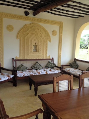 Ein Zimmer im traditionellen Stil, mit einer Sofagarnitur mit gemusterten Kissen, einem Holztisch und einer dekorativen Wandverkleidung.