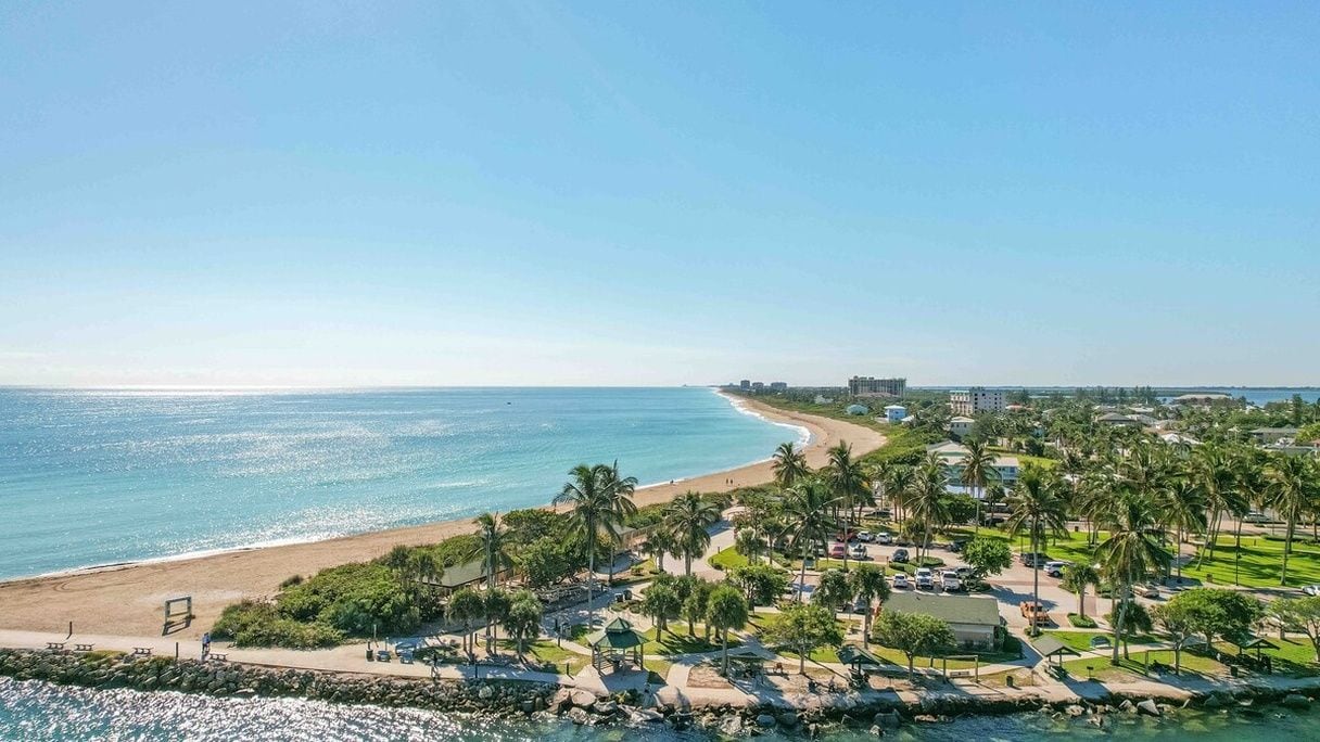 A coastal resort with a beach, palm trees, and a view of the ocean.