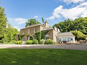 A two-story stone house with a large front lawn and a conservatory. - Eagle Glen Manor House (Blairgowrie)