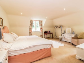 A bedroom with a bed, dresser, vanity, and a window with curtains. - Eagle Glen Manor House (Blairgowrie)