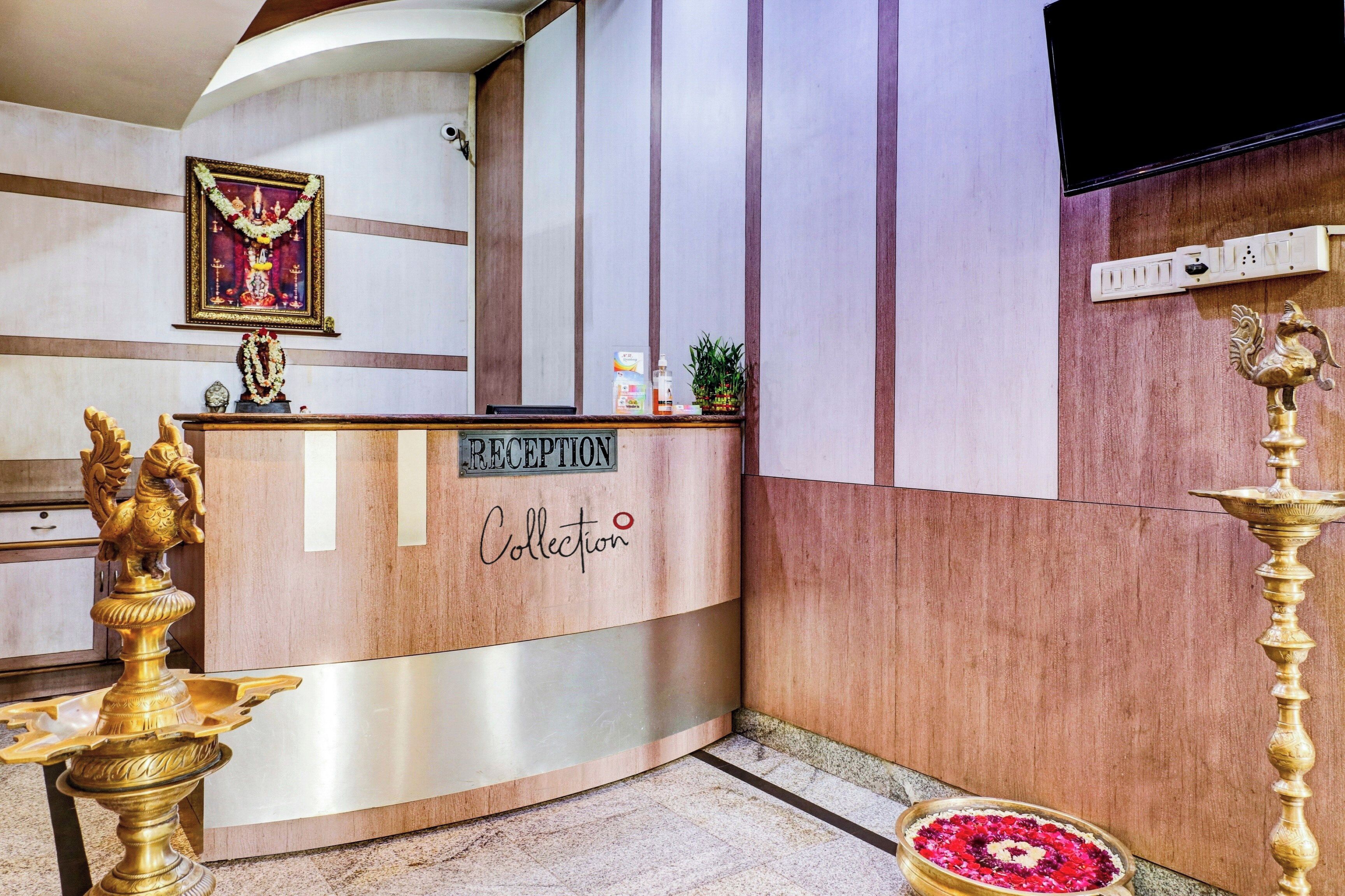 A reception desk with a 'RECEPTION' sign, a framed picture above it, and a decorative golden lamp to the left.