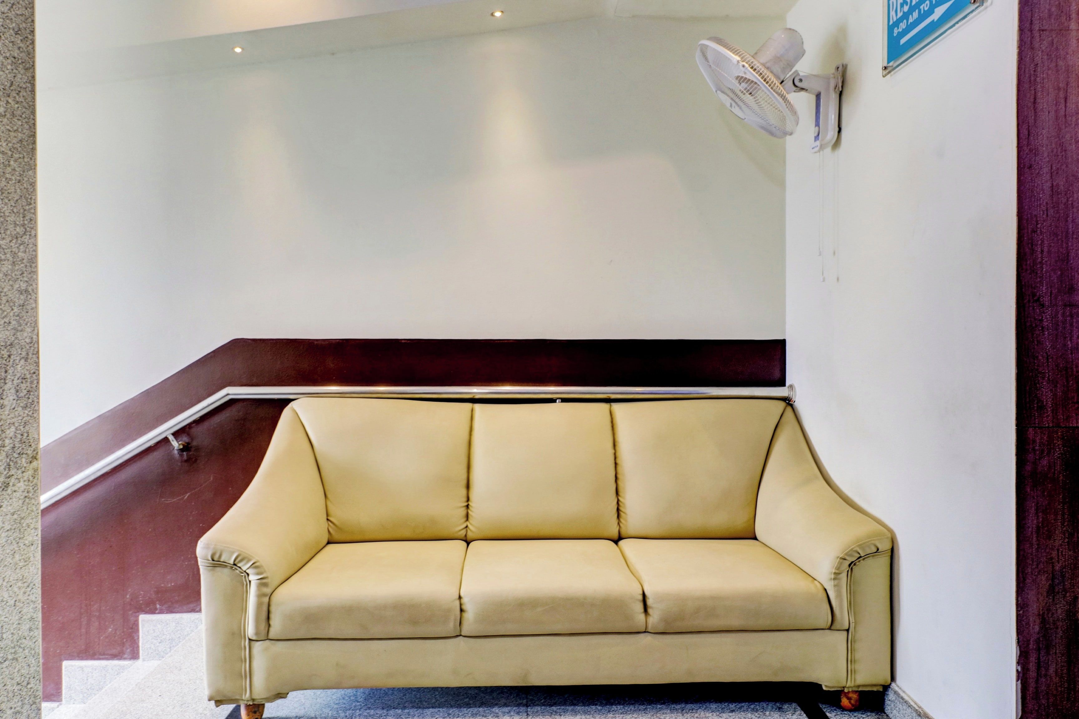 A beige sofa in a lobby area with a staircase in the background.