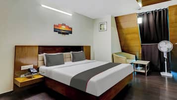 Una habitación de hotel con una cama grande, mesita de noche, lámpara y un cuadro colgado en la pared.