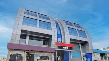 Un edificio moderno con un llamativo letrero de OYO, amplias ventanas y un techo plano.
