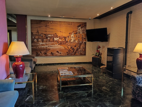 Un vestíbulo moderno con un gran mural, asientos cómodos, una mesita de centro y una chimenea.