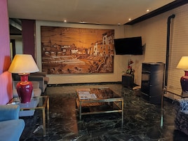 Un vestíbulo moderno con un gran mural, asientos cómodos, una mesita de centro y una chimenea.