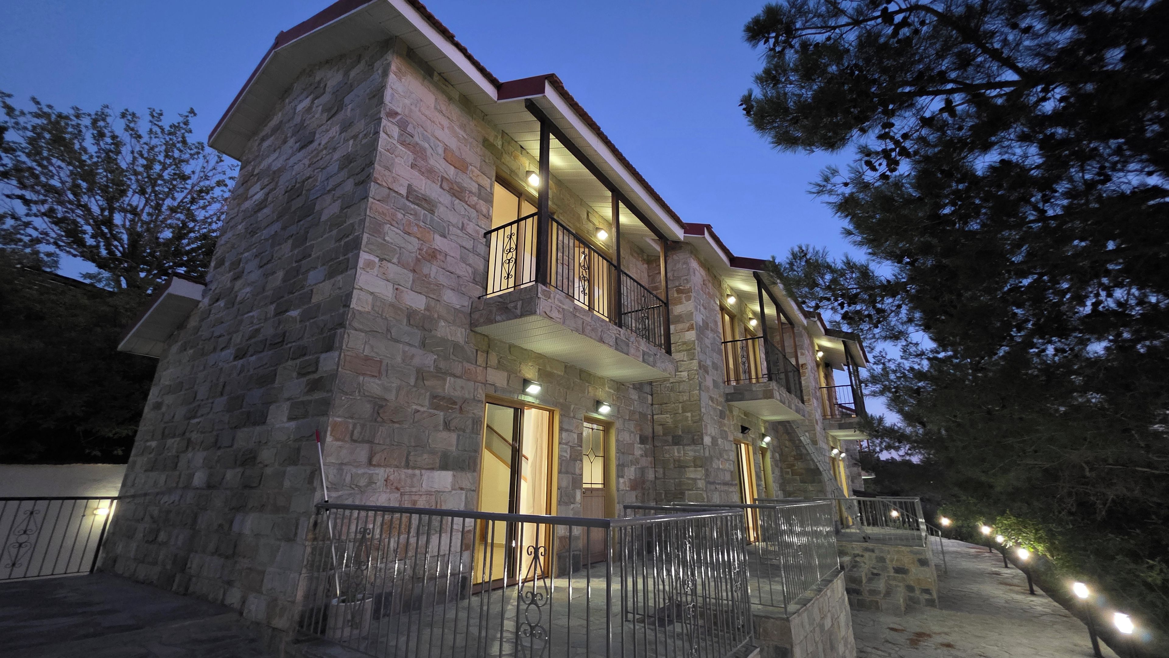 A multi-story stone building with balconies, a gated entrance, and outdoor lighting.