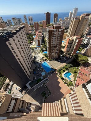 Ein Hochhaus-Hotel mit mehreren Stockwerken, einem Schwimmbad und Blick auf den Ozean.
