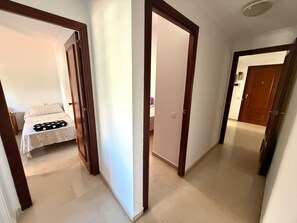 Ein Flur mit einem Bett und einer Tür zu einem weiteren Zimmer.