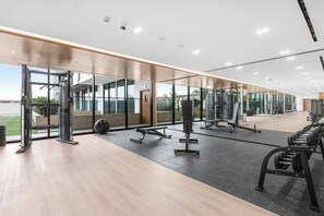 A gym with various exercise equipment, large windows, and a view of the outdoors. - Designer 1BR, Pool View, Finest Renovation JVC (Dubai)