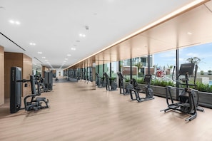 A modern gym with various exercise equipment, large windows, and a view of the outdoors. - Designer 1BR, Pool View, Finest Renovation JVC (Dubai)