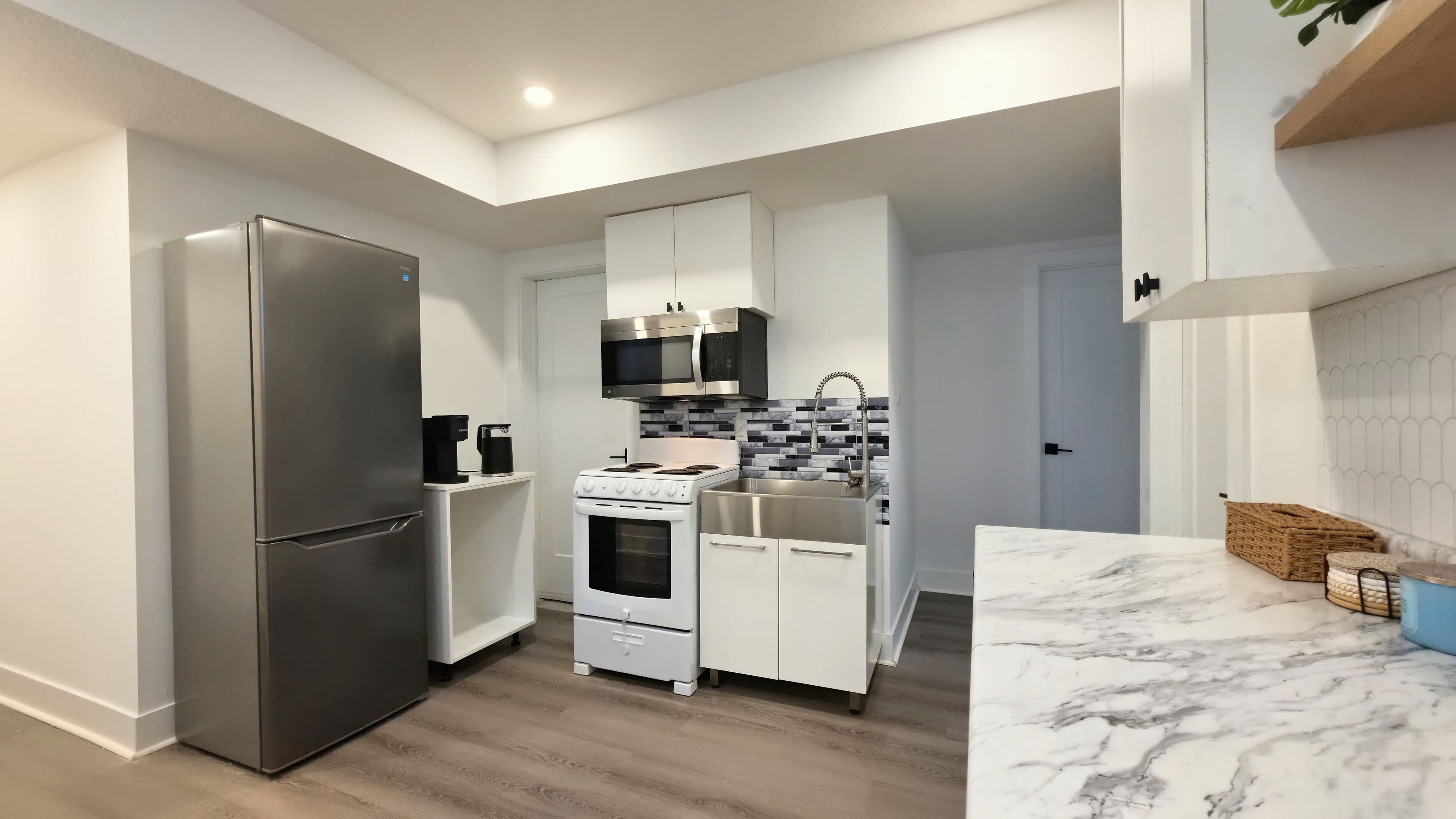 A compact kitchen with a refrigerator, stove, microwave, and sink.