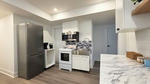 Cocina compacta con refrigerador, estufa, microondas y lavadero.