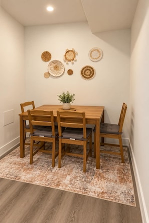 Un comedor con mesa y sillas de madera, una alfombra estampada y platos decorativos colgados en la pared.