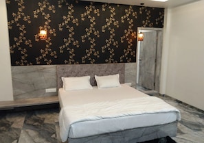 Een slaapkamer met een bed, twee kussens, een marmeren vloer, een donkere, patroonrijke wand en twee wandlampen.