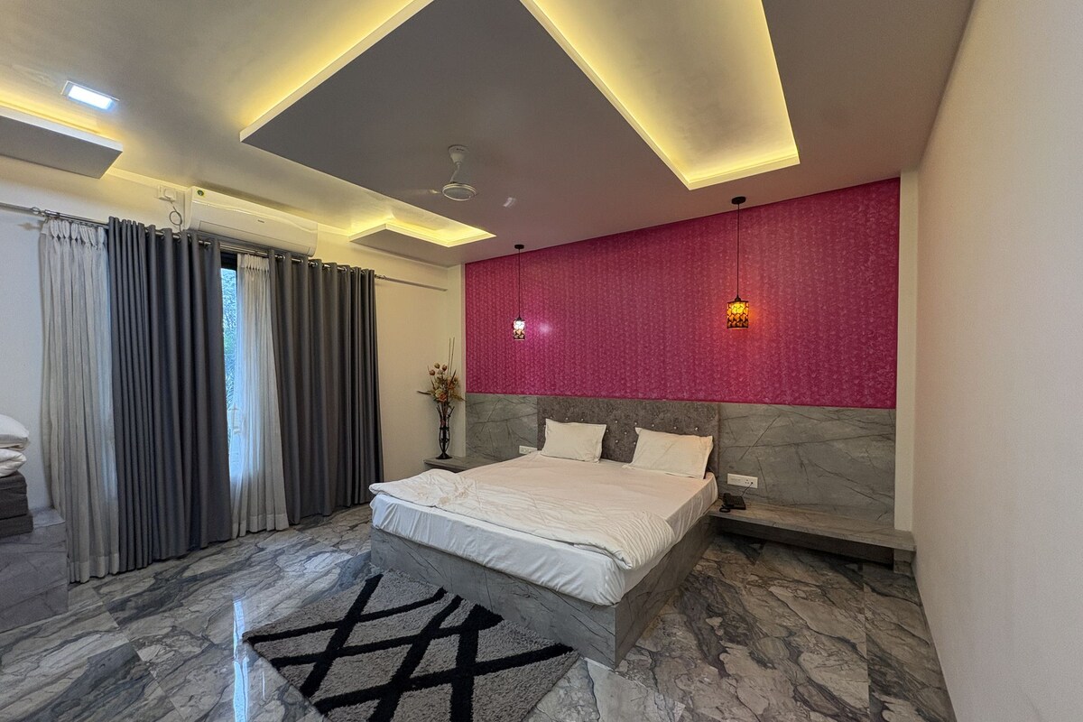 Een moderne slaapkamer met een bed, een marmeren vloer, een rode structuurwand en een plafond met inbouwverlichting.