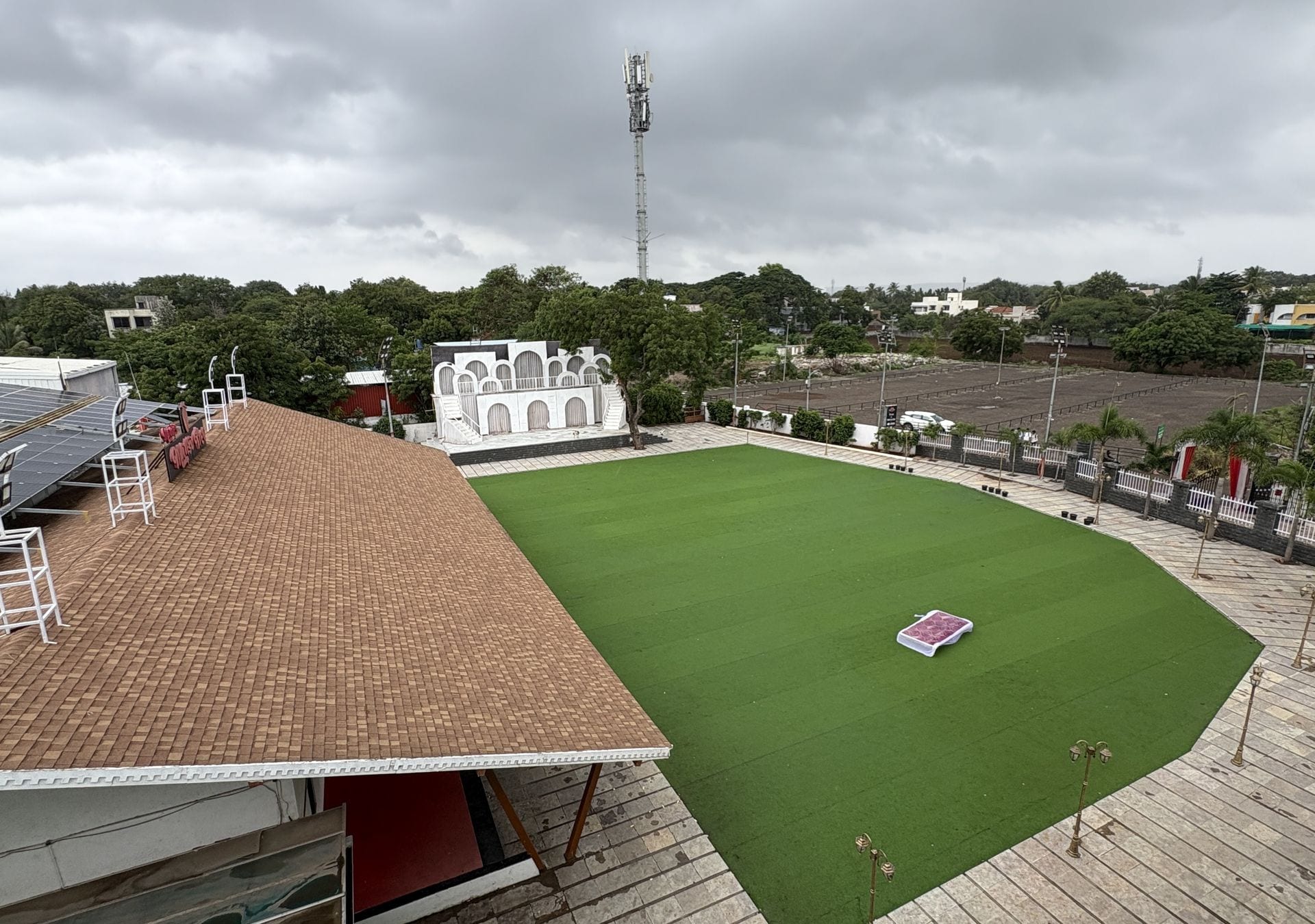 Un estadio con césped verde, techo de ladrillo y un edificio blanco al fondo.