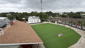 Un estadio con césped verde, techo de ladrillo y un edificio blanco al fondo.
