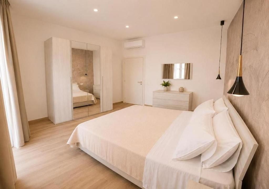 Une chambre d’hôtel moderne avec un grand lit, une commode, un miroir et un luminaire suspendu.