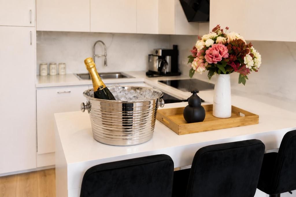 Una cocina con barra, una botella de champán en un cubo de metal y un jarrón con flores sobre una bandeja de madera.