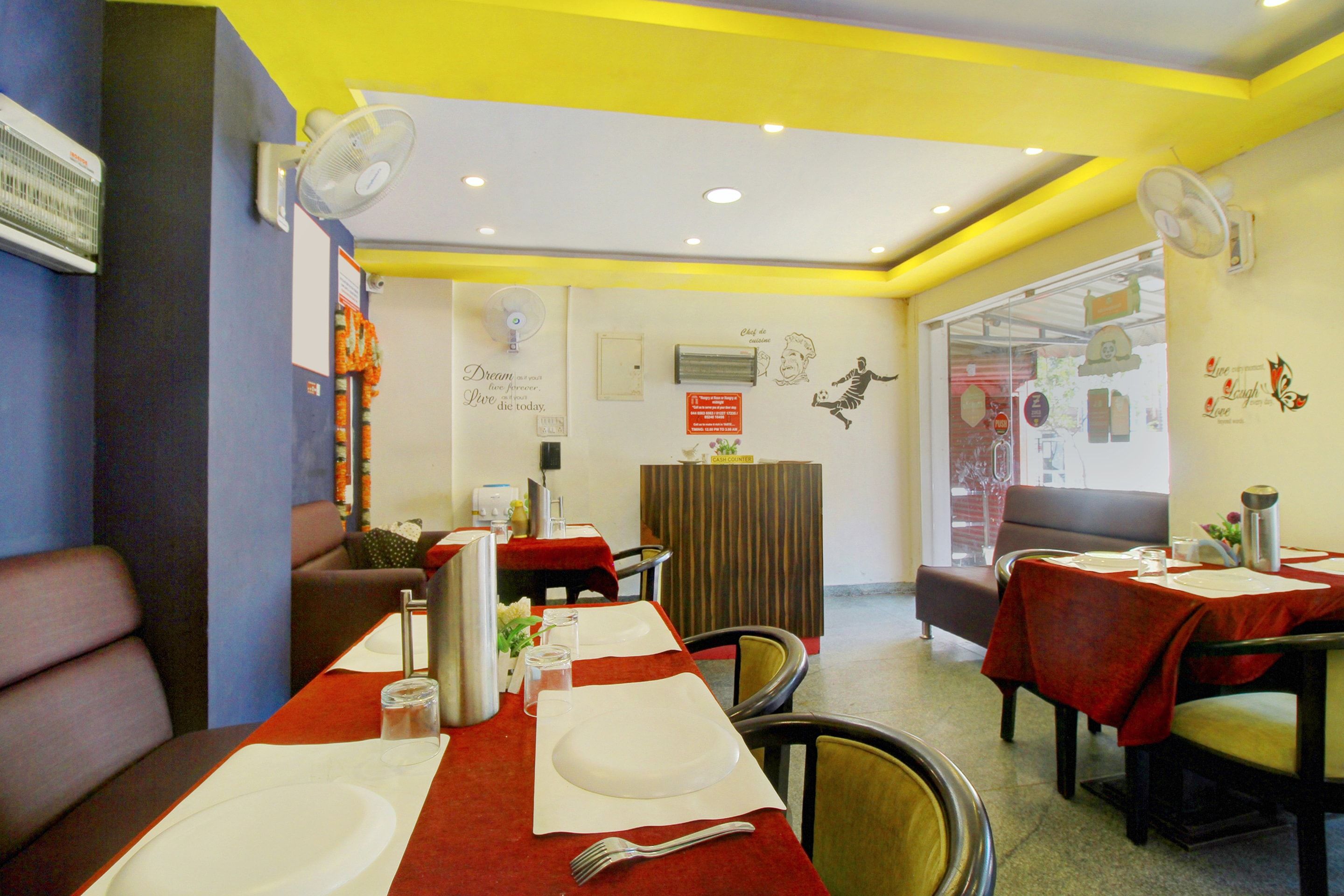 A restaurant interior with tables set for dining, a cash counter, and a wall with a chef illustration.