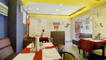 A restaurant interior with tables set for dining, a cash counter, and a wall with a chef illustration.