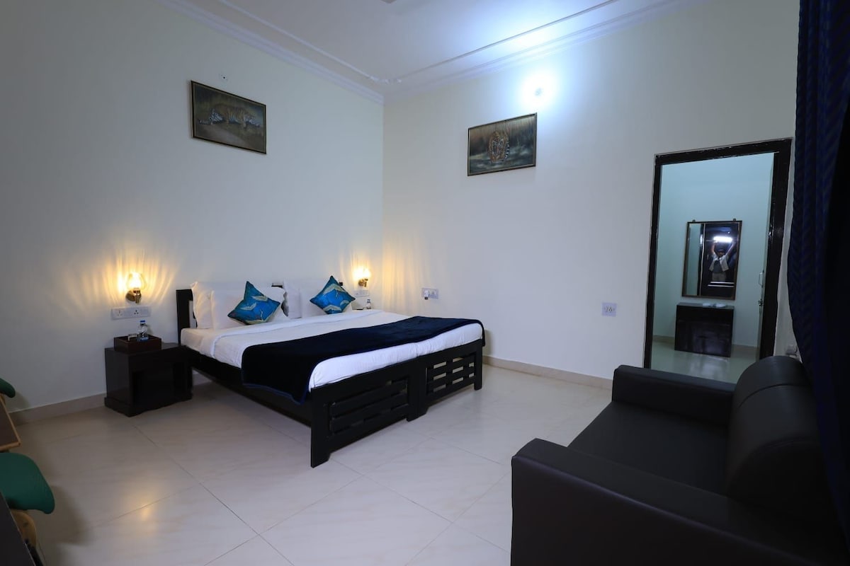 Habitación de hotel con cama, mesitas de noche, un espejo y una zona de estar.