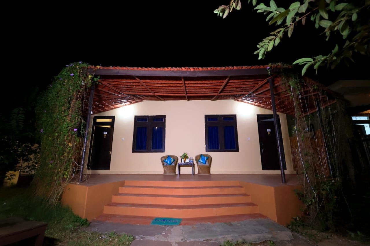 A covered outdoor area with steps leading to a door, two chairs, and a table with a plant.