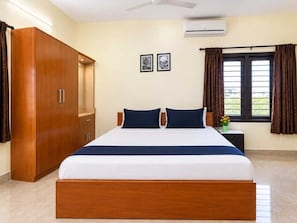 A hotel room with a bed, wardrobe, air conditioning unit, and a window with curtains. - Classic JR Mist Valley inn (Ootacamund)