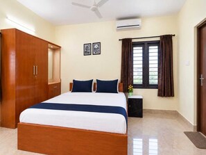 A hotel room with a bed, wardrobe, air conditioning unit, window with curtains, and a ceiling fan. - Classic JR Mist Valley inn (Ootacamund)