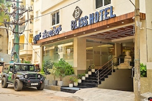 Hotel Bliss con una fachada moderna, una escalera que conduce a la entrada y un SUV estacionado.