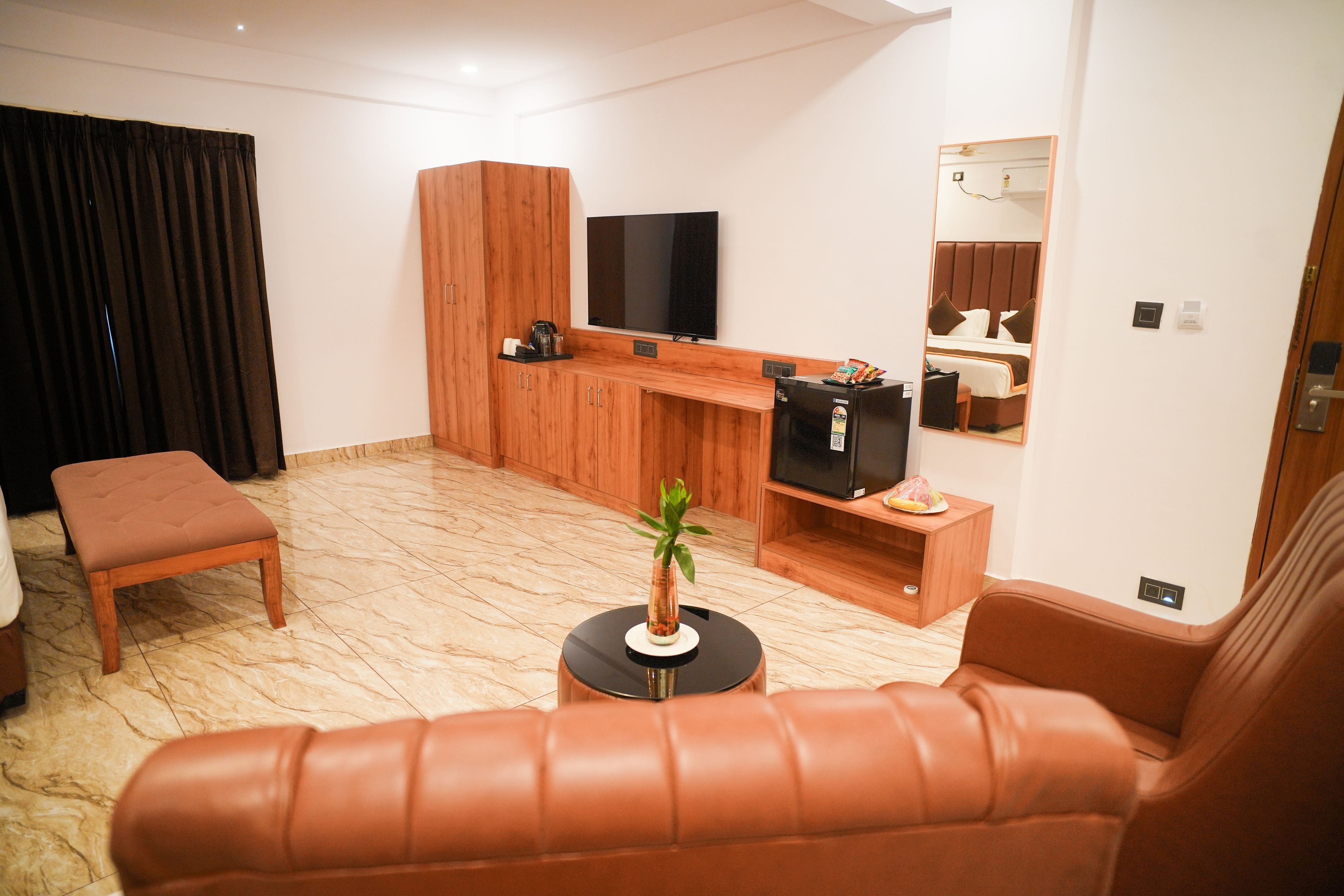 A modern living room with a sofa, a television, a coffee machine, and a small table with a plant.