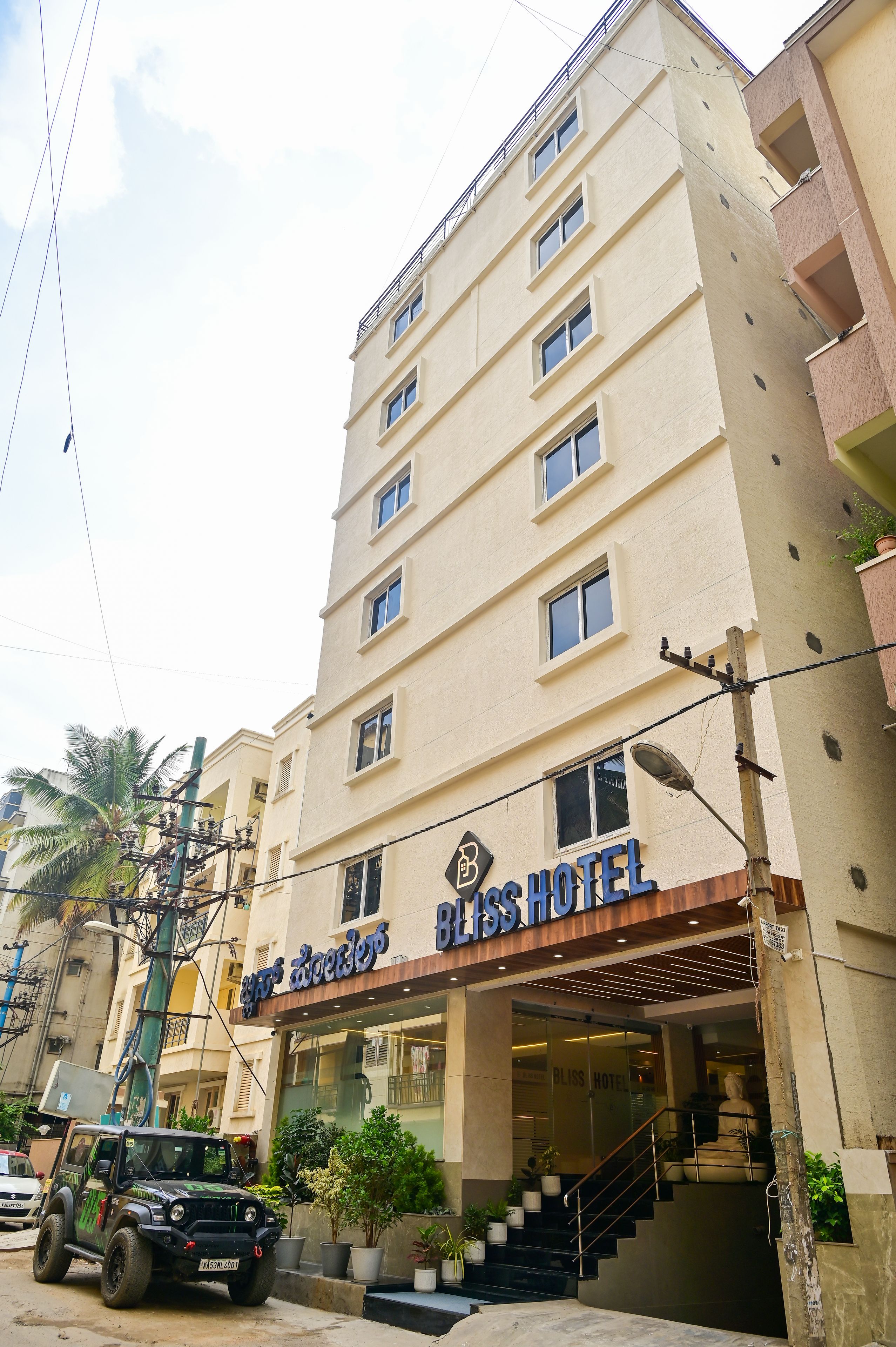A multi-story hotel with a sign reading 'Bliss Hotel' and a staircase leading to the entrance.