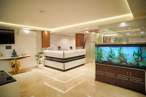 A modern reception desk with a reception area, a large fish tank, and a Buddha statue. - Bliss Hotel (Bengaluru)
