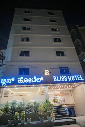 A multi-story hotel with a prominent sign for 'BLISS HOTEL' and a Buddha statue in the entrance area. - Bliss Hotel (Bengaluru)