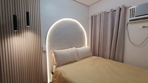 A bedroom with a bed, curtains, a wall-mounted air conditioner, and a light fixture. - Luxurious Casa Karina at SMDC Cheer Residences (Marilao)