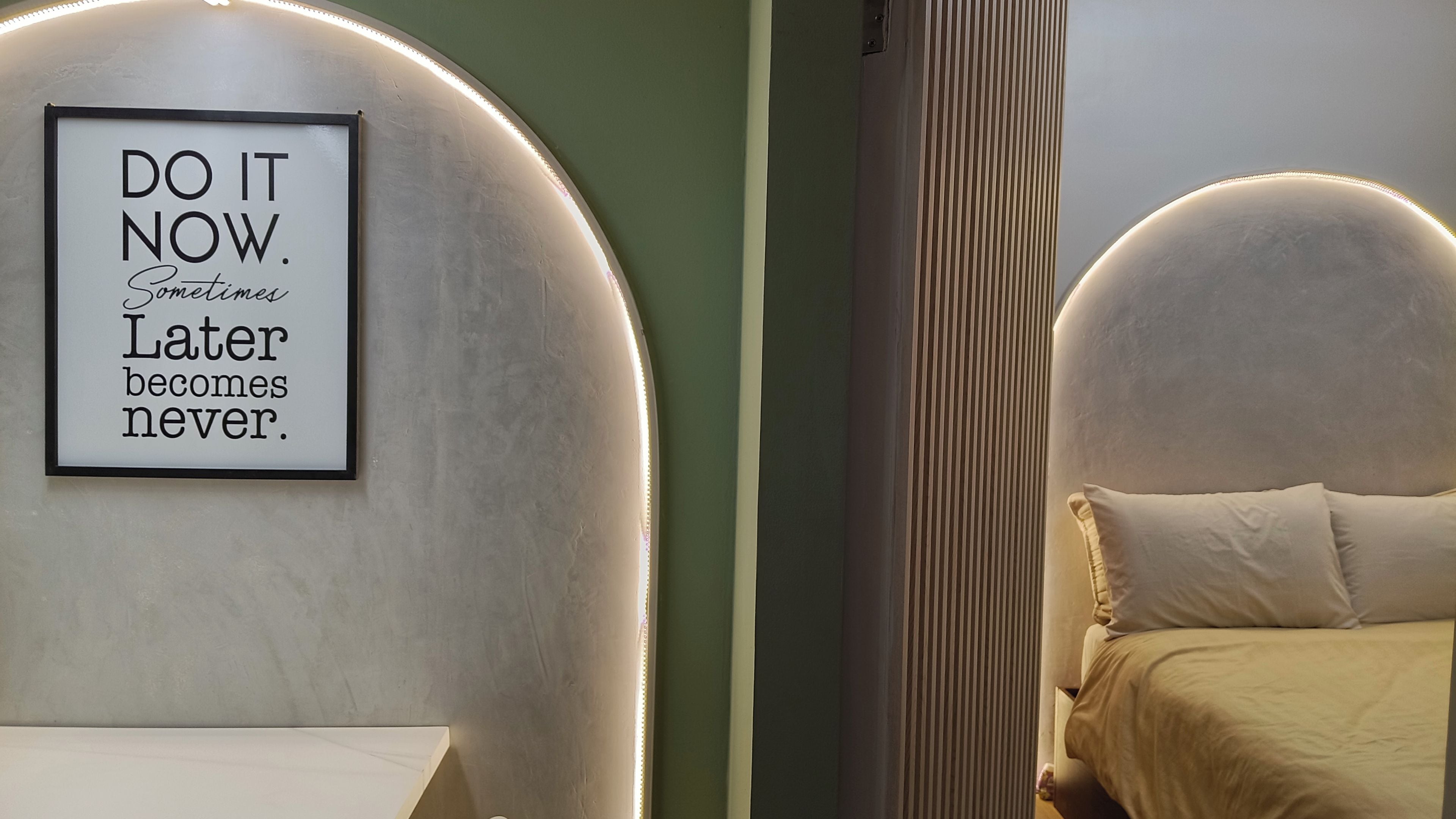 A framed motivational quote on a wall, a bed with a headboard, and a bedside table.