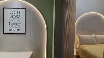 A framed motivational quote on a wall, a bed with a headboard, and a bedside table.