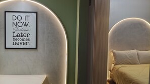A framed motivational quote on a wall, a bed with a headboard, and a bedside table. - Luxurious Casa Karina at SMDC Cheer Residences (Marilao)