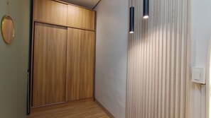 A hallway with a wooden wardrobe, a wall-mounted light fixture, and a door with a light switch. - Luxurious Casa Karina at SMDC Cheer Residences (Marilao)