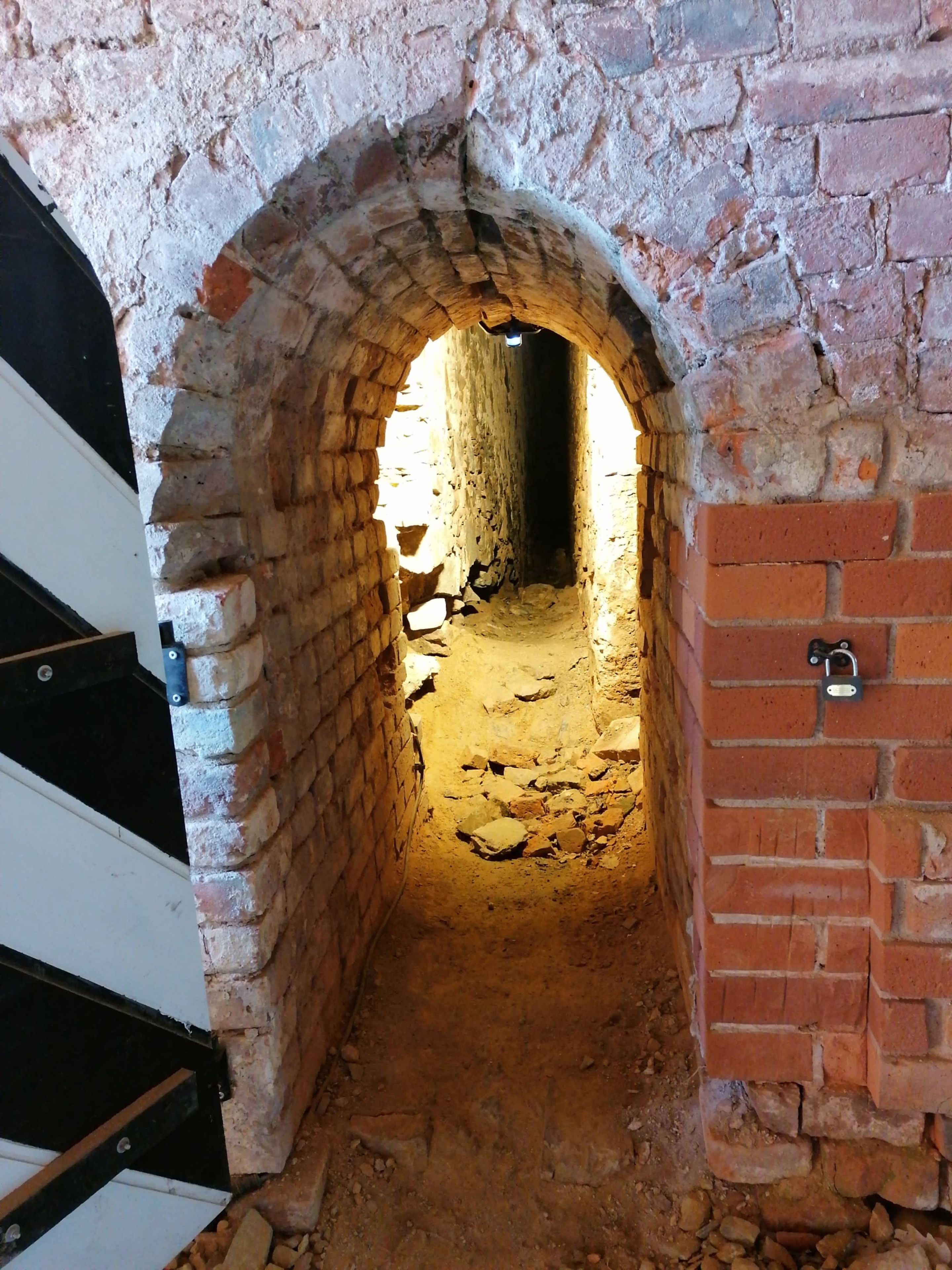 An arched brick passageway leading to a dark interior space.
