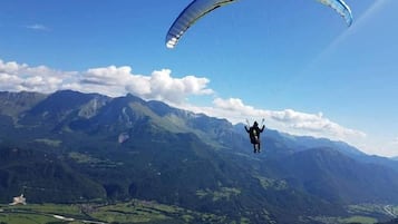 A person paragliding over a mountainous landscape with clear skies.