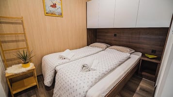 A bedroom with two beds, a wooden ladder, a small plant, and a painting on the wall.